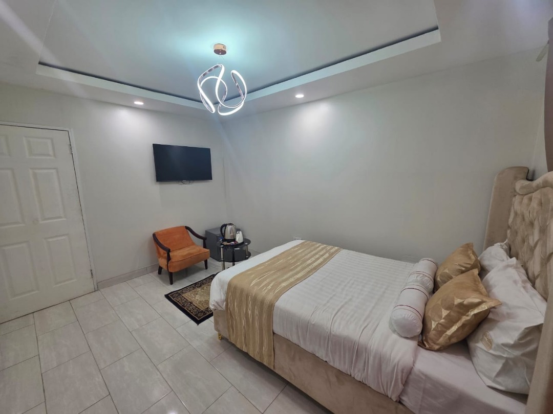 Greys Inn guest room with white bedding, a gold runner and an armchair